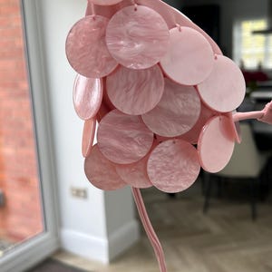 Puede incluir: Objeto decorativo rosa con m&uacute;ltiples discos circulares. Los discos est&aacute;n conectados a un tallo rosa. Los discos tienen un efecto veteado. El dise&ntilde;o es suave y femenino. Adecuado para la decoraci&oacute;n de interiores.