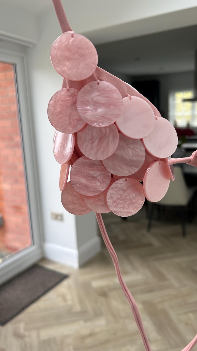 Puede incluir: Objeto decorativo rosa con m&uacute;ltiples discos circulares. Los discos est&aacute;n conectados a un tallo rosa. Los discos tienen un efecto veteado. El dise&ntilde;o es suave y femenino. Adecuado para la decoraci&oacute;n de interiores.