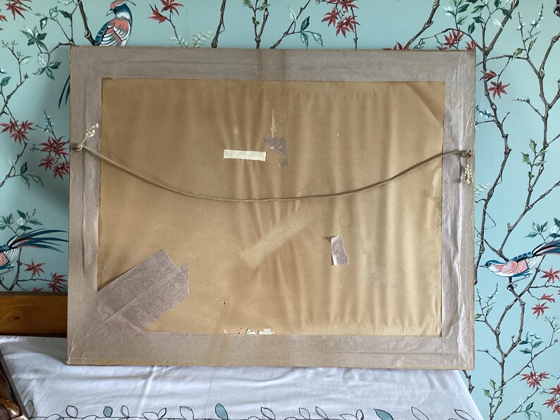 Peut inclure: L'arri&egrave;re d'un tableau encadr&eacute; avec un fond en papier brun. Le cadre est en bois et a une finition brun clair. Il y a deux morceaux de ruban adh&eacute;sif au dos du tableau.