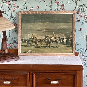 Peut inclure: Une estampe vintage encadr&eacute;e repr&eacute;sentant une sc&egrave;ne de course de chevaux. L'estampe repr&eacute;sente un groupe de chevaux et de cavaliers en course, avec une foule de personnes regardant en arri&egrave;re-plan. L'estampe est dans un cadre en bois avec une finition brun clair.