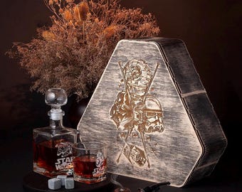 May include: A wooden box with a triangular shape and a Star Wars design. The box has a distressed finish and is engraved with a Stormtrooper and a Rebel pilot. The box is open and shows a glass decanter with a stopper, two glasses, and ice stones. The glasses are engraved with the Star Wars logo. A pipe is also visible in the image.