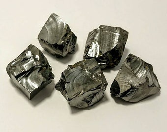 May include: Five rough, gray, metallic, cube-shaped crystals. The crystals have a textured, striated surface.
