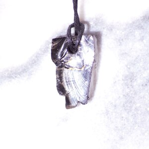 May include: A black obsidian pendant with a silver sheen hangs from a black cord. The pendant is irregularly shaped and has a rough texture.
