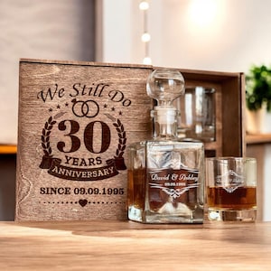May include: A wooden box set with a glass decanter and two glasses. The box is engraved with the text "We Still Do 30 Years Anniversary Since 09.09.1995". The decanter and glasses are engraved with the text "David & Ashley 09.09.1995".