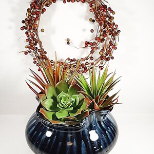 Shown here with succulents tucked in sitting in front of a red berry wreath and surrounded by clear glass beads