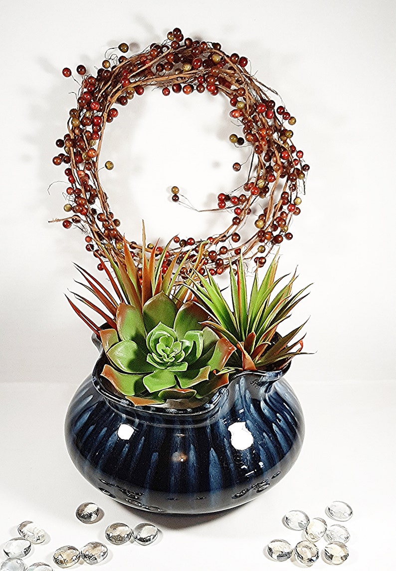 Shown here with succulents tucked in sitting in front of a red berry wreath and surrounded by clear glass beads