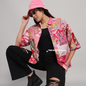 May include: A pink patchwork button-down shirt with a leopard print design, paired with black ripped jeans, a black top, and black boots. The outfit is completed with a pink bucket hat and sunglasses.