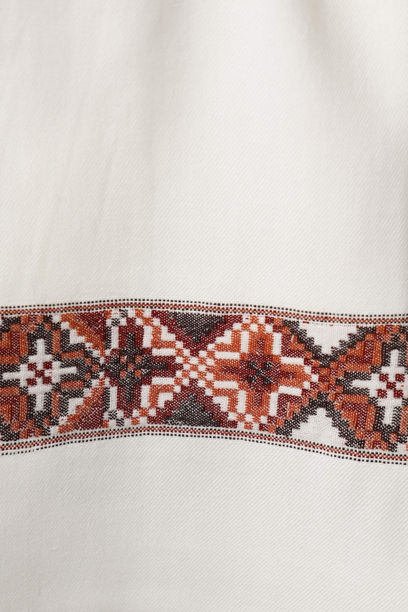 May include: White fabric with a brown and black geometric pattern border.