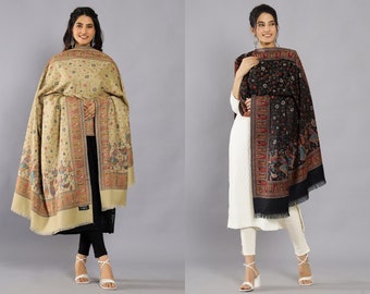 May include: Two women wearing shawls with intricate floral and paisley patterns. The shawl on the left is beige with colorful accents, while the shawl on the right is black with red and blue accents.