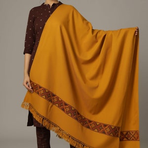 May include: A mustard yellow shawl with a brown and orange embroidered border and fringe.
