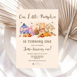 Peut inclure: Une invitation beige avec le texte "Our Little Pumpkin is Turning One". La carte présente des illustrations des personnages de Winnie l'Ourson, des citrouilles et des abeilles. L'invitation comprend les détails de l'événement.