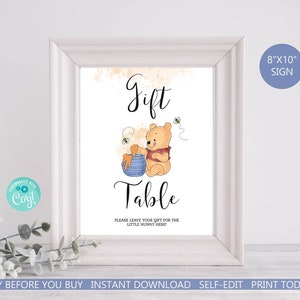 May include: Printable 8x10 inch Winnie the Pooh themed sign that says "Gift Table" with a cartoon image of Winnie the Pooh holding a pot of honey. The sign has a light yellow background with a watercolor effect and says "Please leave your gift for the little hunny here!"