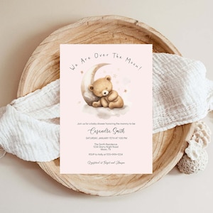 May include: A pink baby shower invitation with a cartoon illustration of a brown teddy bear sleeping on a crescent moon. The text reads "We Are Over The Moon!" and includes the name "Casandra Smith", the date and time of the shower, the location, and RSVP information.
