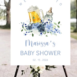 May include: Welcome to Marissa's Baby Shower sign with a blue and white floral design, a beer mug, and a baby bottle. The date of the shower is 02.15.2024.