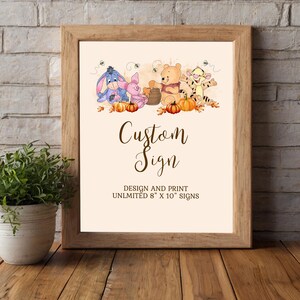 Puede incluir: Un letrero personalizado enmarcado con ilustraciones de personajes de Winnie the Pooh, calabazas y abejas. El letrero dice "Custom Sign" con el texto "DESIGN AND PRINT UNLIMITED 20 x 25 cm SIGNS". El marco es de madera marrón claro.