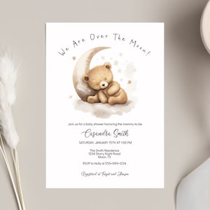 May include: A baby shower invitation with a cute illustration of a brown teddy bear sleeping on a crescent moon. The text reads "We Are Over The Moon!" and includes the name "Casandra Smith", the date and time of the shower, the location, and RSVP information.