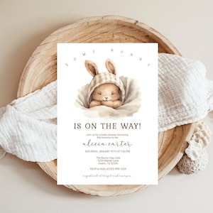 May include: A baby shower invitation with a watercolor illustration of a sleeping bunny wearing a plaid bonnet. The text reads "Some Bunny Is On The Way!" and includes the name "alicia carter" and details for the event.