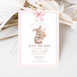 May include: Pink and white gingham baby shower invitation with a watercolor illustration of a brown bunny holding a bouquet of pink flowers. The text reads "Some Bunny is on the Way!" and includes the name Maria Campbell, the date and time of the event, and the location.