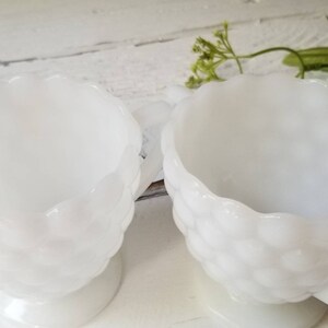 May include: A set of two white milk glass creamer and sugar bowls with a textured, bubbled design.
