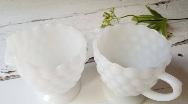May include: A set of two white milk glass creamer and sugar bowls with a textured, bubbled design.