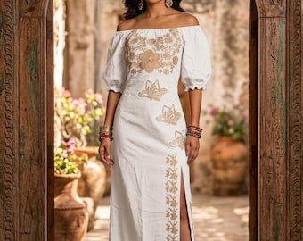 May include: A white off-the-shoulder midi dress featuring gold floral and butterfly embroidery on the bodice and a vertical floral pattern along the side slit. The dress has puff sleeves and a straight skirt silhouette with a high side leg opening.