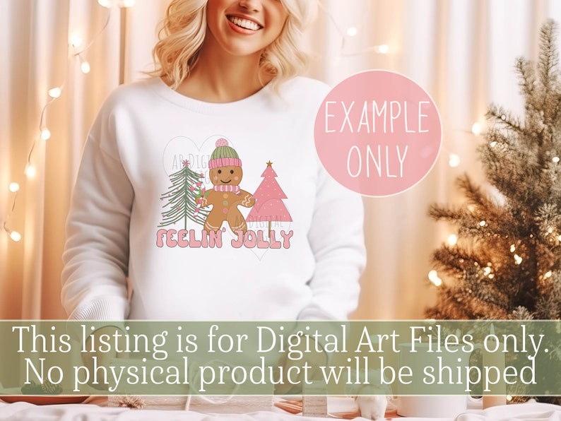 May include: A white sweatshirt with a pink heart design featuring a gingerbread man, two Christmas trees, and the text "Feelin' Jolly".