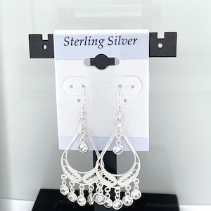 May include: Sterling silver dangle earrings with a teardrop design and clear crystal accents. The earrings have a delicate filigree pattern and are hanging from a hook.