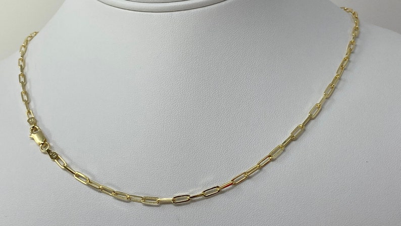 K&ouml;nnte beinhalten: Eine goldene Kettenkette im Box-Ketten-Stil. Die Kette besteht aus kleinen, rechteckigen Gliedern.