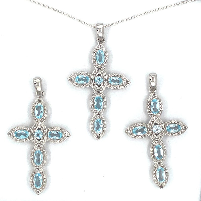 Puede incluir: Tres colgantes de plata en forma de cruz engastados con topacios azules. Las cruces est&aacute;n engastadas con piedras ovaladas y tienen un dise&ntilde;o delicado e intrincado.