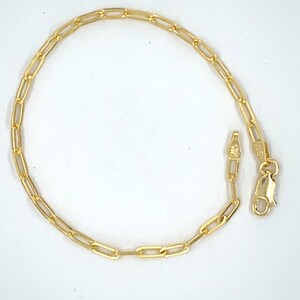 K&ouml;nnte beinhalten: Ein goldenes Kettenarmband mit einem Karabinerverschluss. Die Kette besteht aus kleinen, rechteckigen Gliedern.