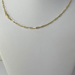 K&ouml;nnte beinhalten: Eine goldene Kettenkette mit einem einfachen, verlinkten Design. Die Kette befindet sich auf einer wei&szlig;en Mannequin-B&uuml;ste.
