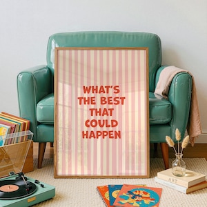 May include: A framed poster with the text "WHAT'S THE BEST THAT COULD HAPPEN" in red, set against a pink and cream striped background. The poster is displayed in a room with a teal armchair, a record player, and vinyl records.