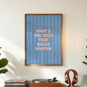 Puede incluir: Una impresi&oacute;n enmarcada con el texto "WHAT'S THE BEST THAT COULD HAPPEN" en letras rosas sobre un fondo a rayas azules. El marco es marr&oacute;n, y la impresi&oacute;n se muestra encima de un tocadiscos y unos auriculares.