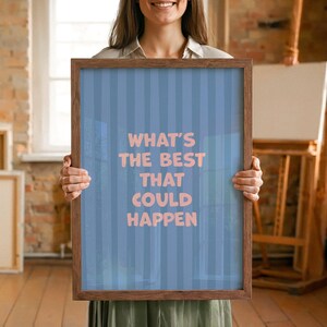 Puede incluir: Una impresi&oacute;n enmarcada con el texto "WHAT'S THE BEST THAT COULD HAPPEN" en letras rosas. El fondo es azul claro con rayas verticales. El marco es de madera marr&oacute;n.