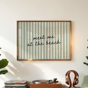 Könnte beinhalten: Ein gerahmter Druck mit einem braunen Holzrahmen. Das Kunstwerk zeigt ein vertikales Streifenmuster in Hellgrün und Creme. Der Text "meet me at the beach" ist in einer Schreibschrift geschrieben.