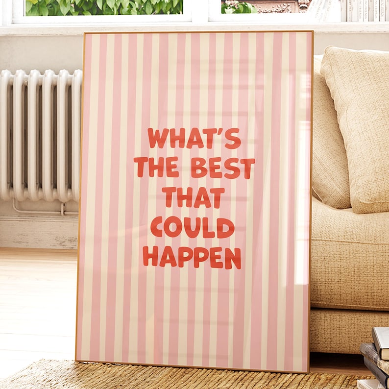 May include: A framed print with a pink and cream striped background. Bold red text reads "WHAT'S THE BEST THAT COULD HAPPEN". The artwork is displayed in a room with a window, radiator, and a beige sofa.