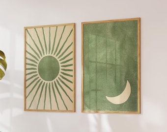 May include: Two framed art prints. One shows a green sunburst on a beige background. The other has a green background with a white crescent moon. Both are in wooden frames, forming a matching set for wall decor.