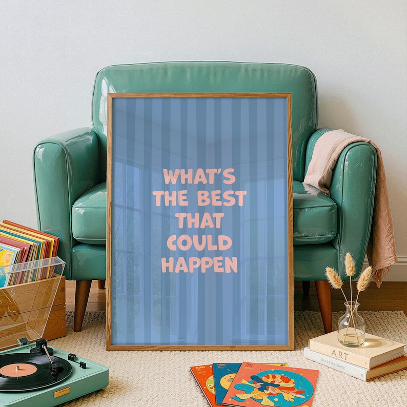 Puede incluir: Un p&oacute;ster enmarcado con el texto "WHAT'S THE BEST THAT COULD HAPPEN" en letras rosas sobre un fondo azul a rayas. El p&oacute;ster est&aacute; apoyado contra un sill&oacute;n verde azulado. Un tocadiscos y discos de vinilo est&aacute;n en primer plano.