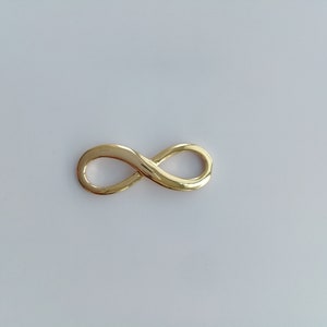 May include: A gold infinity symbol charm. The charm is smooth and shiny.