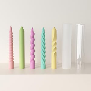 May include: A collection of pastel-colored candles in various shapes. The candles include pink, green, purple, and yellow twisted and straight designs. Two clear cylindrical candle holders are also present.