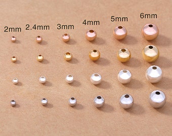 May include: Assortment of round metal beads in gold, silver, and rose gold finishes. The beads are arranged in rows by size, from 2mm to 6mm.