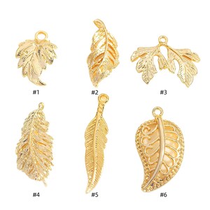 Peut inclure: Six breloques en forme de feuille dorées avec des motifs différents. Les breloques sont numérotées de 1 à 6.