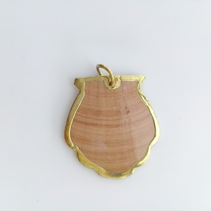 May include: A gold-coloured pendant with a light brown, textured, shell-like design.