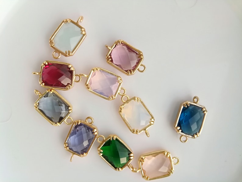 Puede incluir: Surtido de conectores de piedras preciosas de vidrio de colores con engastes de metal dorado. Los conectores tienen forma de rect&aacute;ngulos con esquinas redondeadas y un dise&ntilde;o facetado. Los colores incluyen rosa, azul, verde, morado, rojo y transparente.