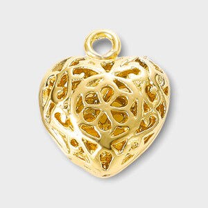 May include: A gold-colored heart-shaped pendant with a delicate, intricate filigree design. The pendant has a loop at the top for attaching to a chain or cord.
