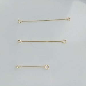 May include: Three gold jump rings, each with a different length. The jump rings are on a white background.