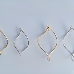 May include: Four different sized, twisted wire hoops in gold and silver. The hoops are all in the shape of a teardrop.