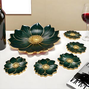 May include: A decorative set featuring a large, dark green flower-shaped serving dish and six matching coasters. The dish and coasters have gold-colored edges and centers, creating an elegant contrast. The set is designed for serving or display.