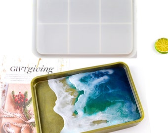 May include: A white silicone mould for making resin trays. The mould is divided into six sections. A finished resin tray with a blue and white ocean wave design is shown next to the mould.