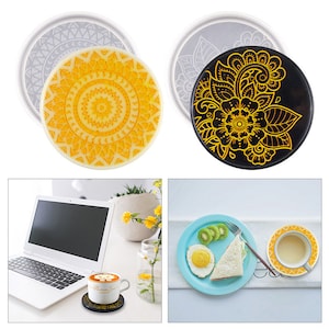 May include: Two round silicone coasters with intricate designs. One coaster features a black background with a yellow floral pattern. The other coaster features a yellow mandala pattern on a white background.